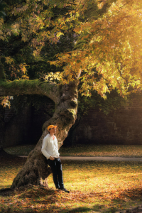 Bild-Nr: 12905786 Mann lehnt an knorrigen Baum im herbstlichen Park Erstellt von: Smileus